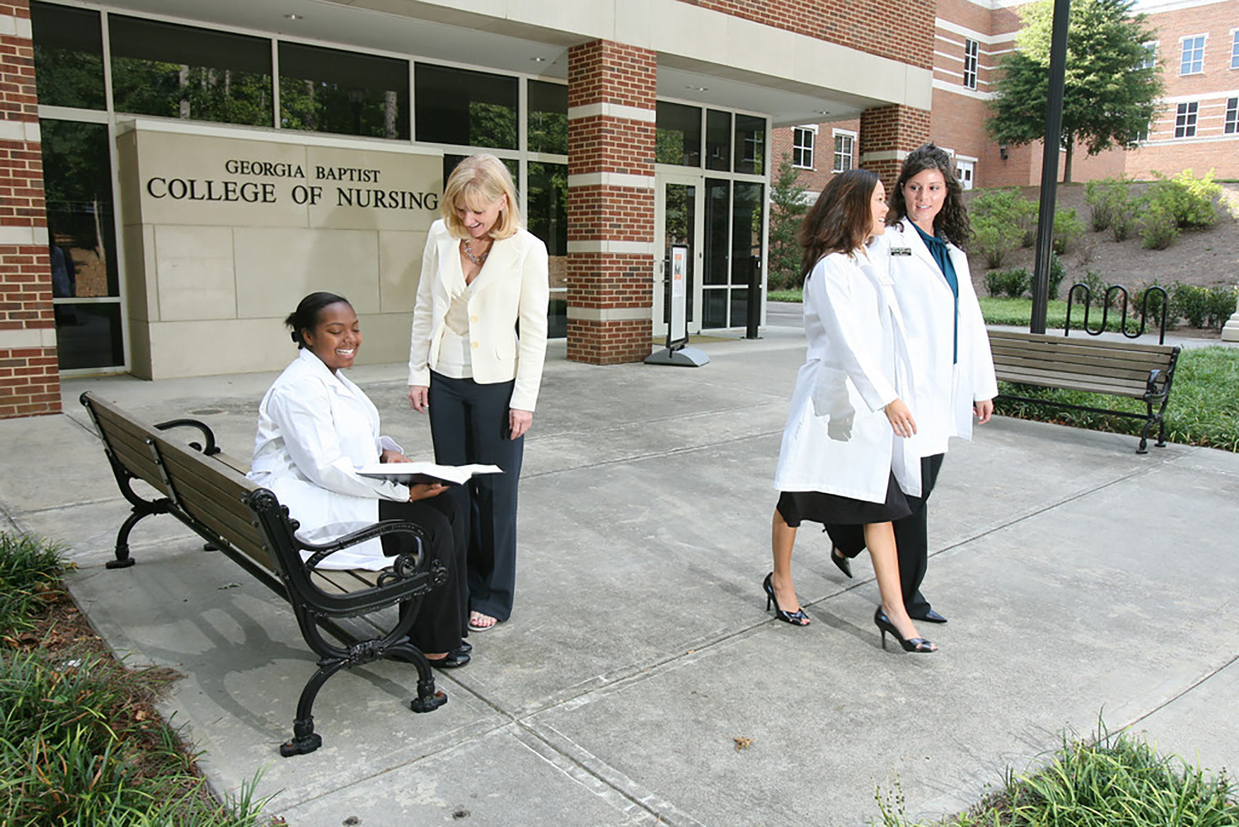 Four women outside of the College of Nursing building