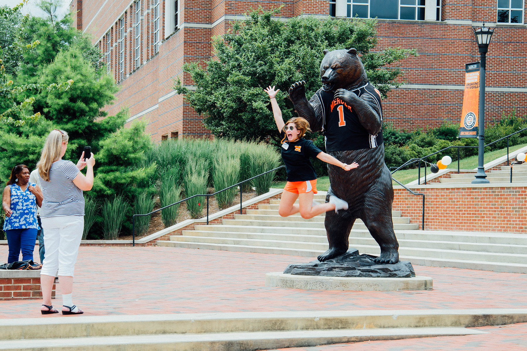 Student jumping in front of bear statue